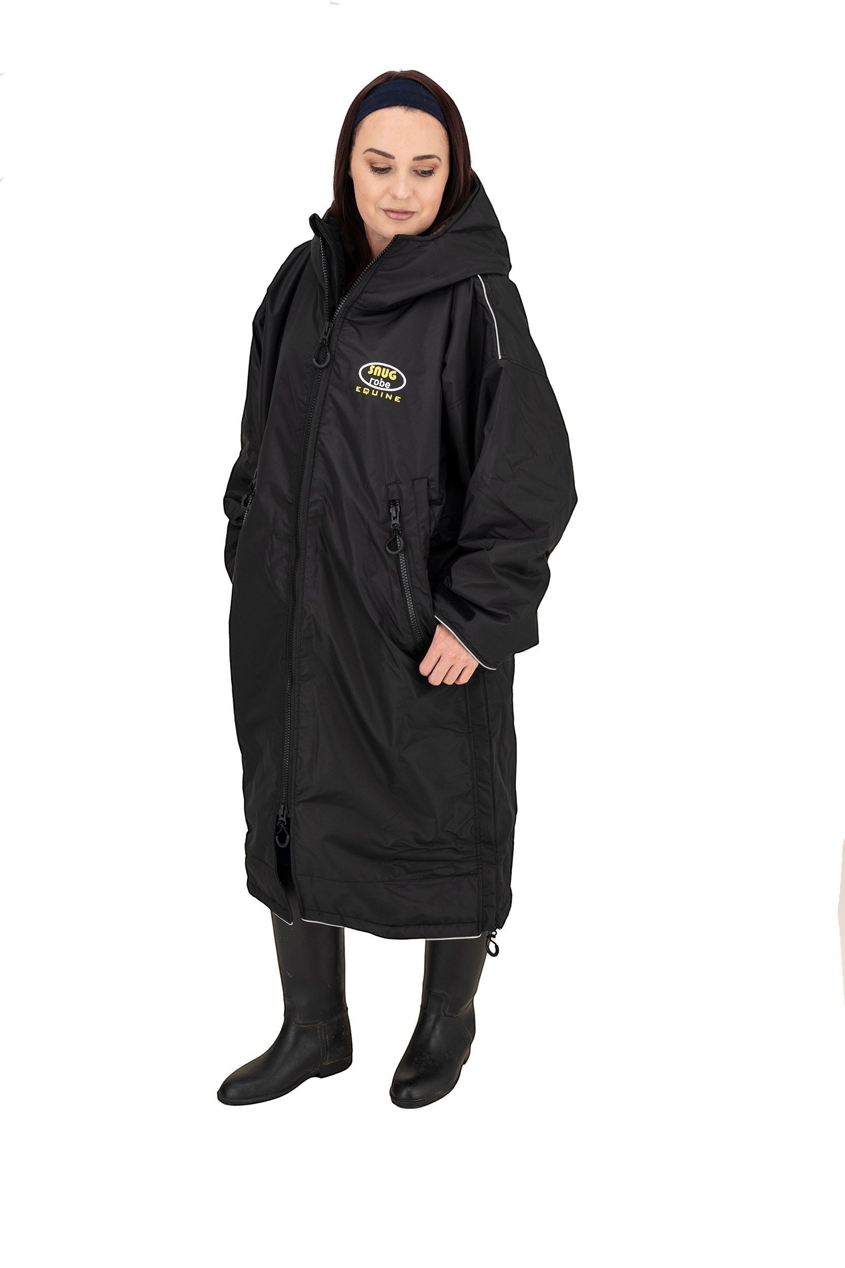 Snugrobes black waterproof equestrian robe with fleece lining, hood, and reflective piping. Model wears black boots.