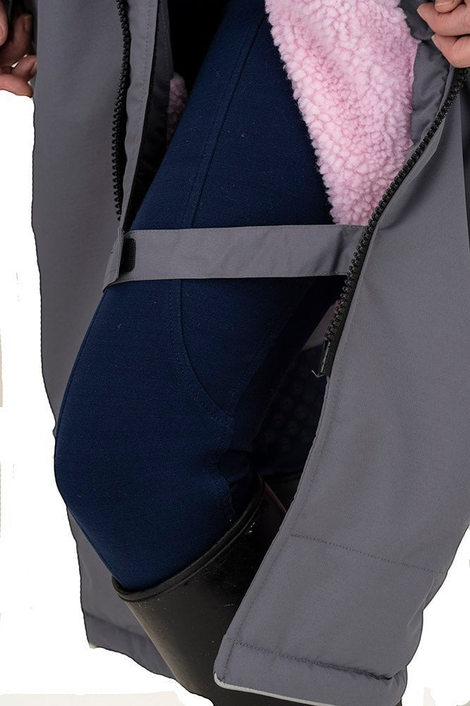 Snugrobes grey waterproof equestrian robe with pink fleece lining, showing navy riding breeches and black boots.