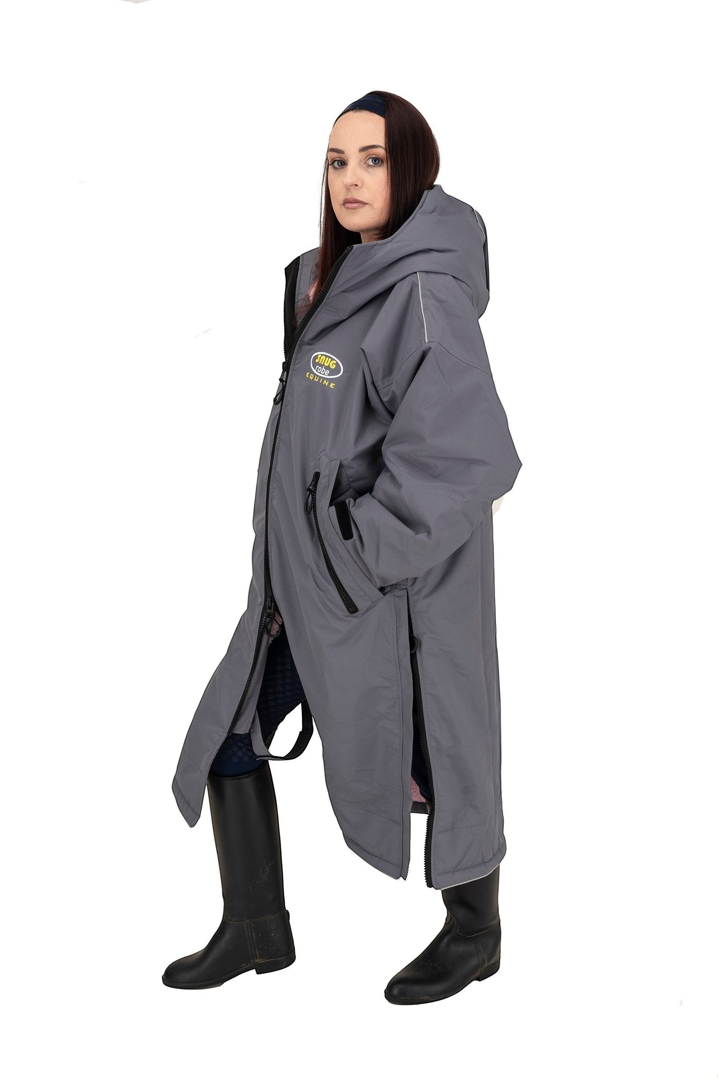 Snugrobes grey waterproof equestrian robe with fleece lining, hood, and side zips. Model wears black boots.